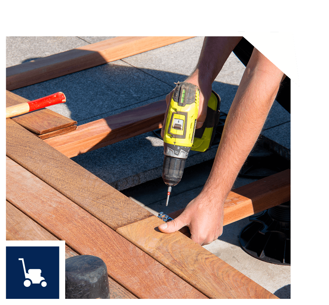 Person using a yellow cordless drill to fasten screws into wooden planks on a construction site.