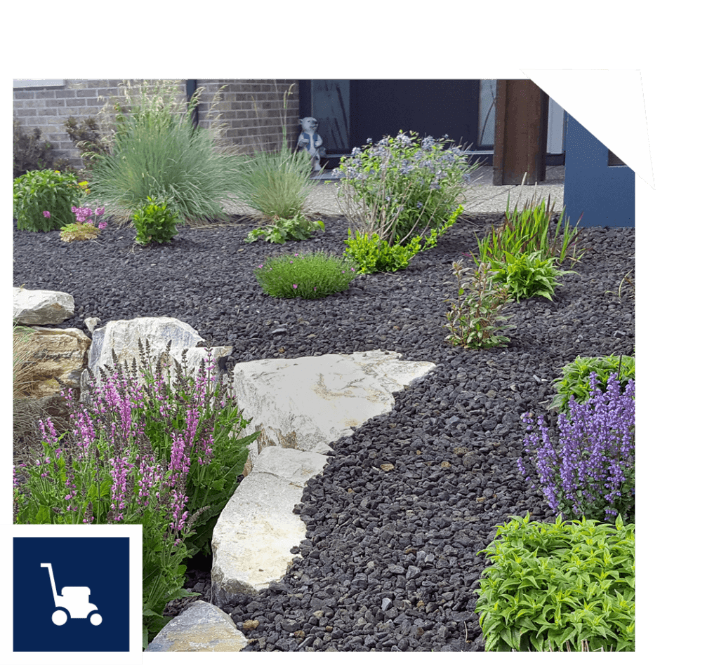A landscaped garden with dark gravel, large rocks, and a variety of green shrubs and purple flowering plants. A small statue is visible near a brick wall in the background. A lawnmower icon is at the bottom left corner.